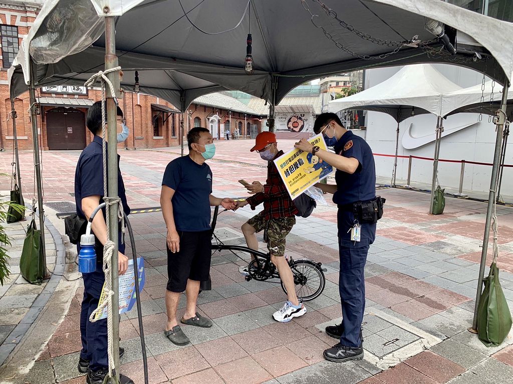 照片1 臺北市保安警察大隊員警手持宣導海報，以標語提醒民眾，小心防疫期間常見的簡訊詐騙。